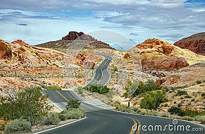 Long winding highway with ups and downs, cloudy blue sky. Valley of Fire Nevada, USA Stock Photo