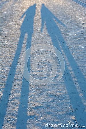 Long winter shadows in the snow of two people standing Stock Photo