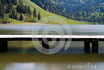 Long wooden boardwalk on a calm and placid mountain lake with a great view Stock Photo