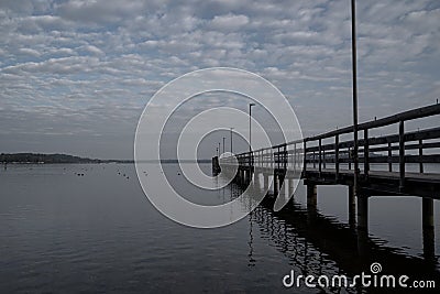 Long wooden jetty in the lake in the morning Stock Photo