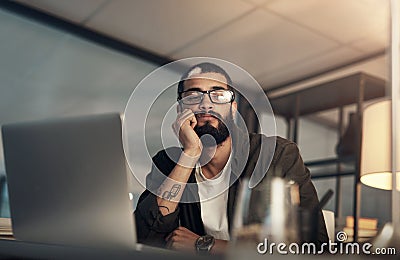 Are long working hours making me miss out on life. a young businessman looking uncertain while working late at night in Stock Photo