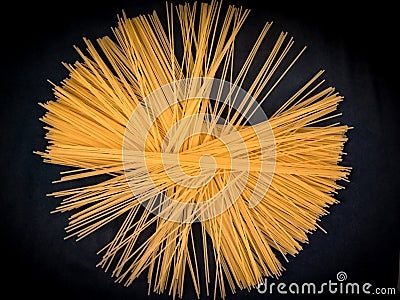 Long yellow spaghetti on black background. Arrange spaghetti in a circle Stock Photo