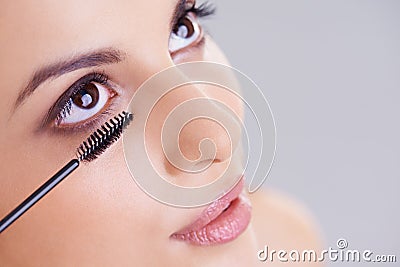 For longer, thicker lashes. a beautiful young woman applying mascara to her lashes. Stock Photo
