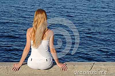 Longhaired girl sitting by the sea Stock Photo