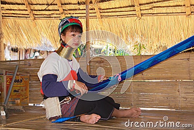 LONGNECK KAREN VILLAGE, THAILAND - DECEMBER 17. 2017: Long neck woman doing handwork under thatched roof Editorial Stock Photo