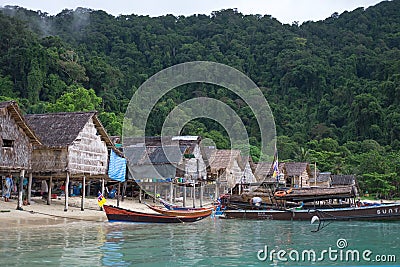 Longtail boat parked on sea have old village and forest on mount Editorial Stock Photo