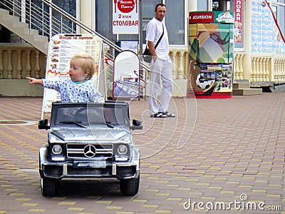 Loo Sochi, Russia, 08.31.2017: A little blond boy rides an electric car for the first time Editorial Stock Photo