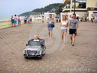 Loo Sochi, Russia, 08.31.2017: A little blond boy rides an electric car for the first time Editorial Stock Photo