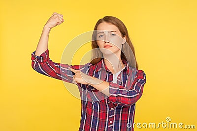 Look, I`m strong woman! Portrait of self-confident ginger girl in casual shirt pointing at biceps, feeling power and energy to Stock Photo