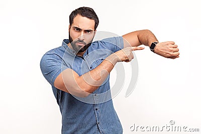 Look at time! Impatient bossy man with beard pointing finger at wrist watch and looking annoyed and displeased, showing clock to Stock Photo