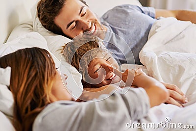 Look who sneaked in here. a cheerful young family relaxing in bed at home during the day. Stock Photo