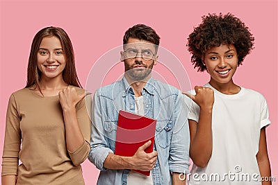 Look at this wonk. Cheerful women point with thumb at guy who stands between them, has puzzled indecisive expression Stock Photo