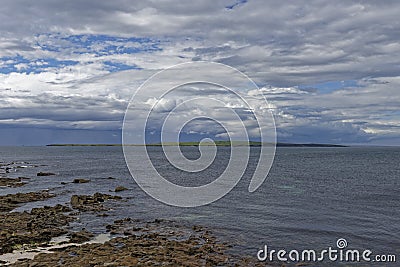 Looking across to the the island of Stroma, part of the Orkneys from the rocky beach at John Oâ€™Groats. Stock Photo