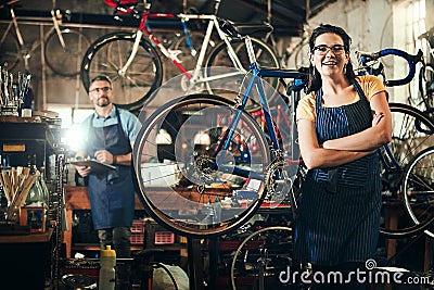 Looking for the bike expert Youve found her. Portrait of a young woman working in a bicycle repair shop with her Stock Photo