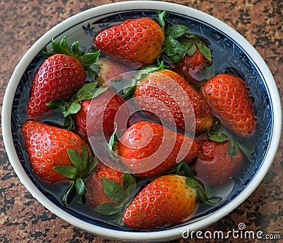 Looking down from above onto a bowlful of fresh strawberries on a table Stock Photo