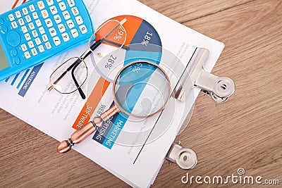 Looking down and shooting a stack of business-related documents on the table and the magnifying glass and calculator on the docume Stock Photo