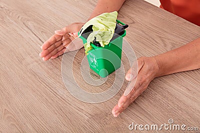 Looking down shot Chinese women`s hands pampering the green bin. The Chinese characters on the trash can mean`Kitchen waste`and `E Stock Photo