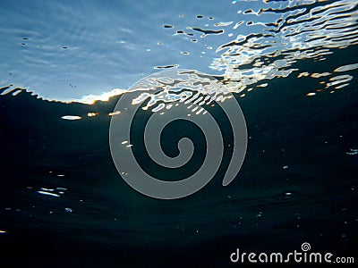 Looking through ocean water at blue sky with water ripples Stock Photo