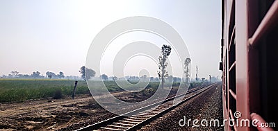 Looking out of the window of a express train of Indian railways with a view of green farm lands Stock Photo