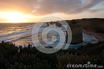 Looking over a green shrub at the sunset at Twelve Apostles on the Great Ocean Road in Australia Stock Photo