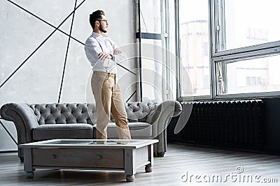 Looking perfect. Full length of handsome young man looking away while standing at home. Stock Photo