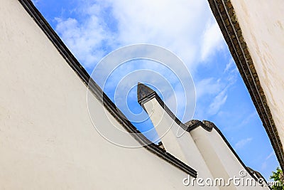 Looking skyward in a hutong alley between two white traditional brick concrete walls and tiles Stock Photo