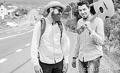 Looking for transport. Men edge road hitchhiking. Friends gathered to travel together. Travelers with backpack and Stock Photo