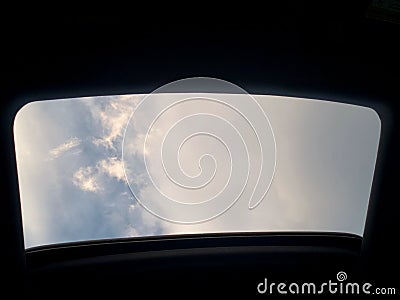 Looking up at a clouded sky heaven through car sun roof Stock Photo