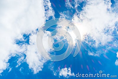 Looking up at sun ray behind cloud with light flare and blue sky Stock Photo