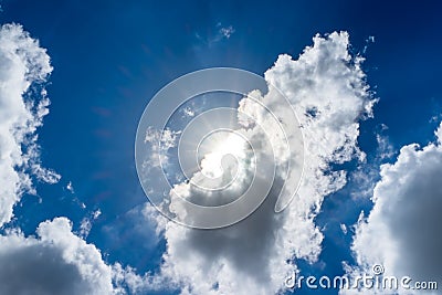 Looking up at sun ray behind cloud with light flare and blue sky Stock Photo