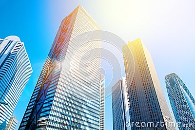 Looking up view in financial district, the silhouettes of skyscrapers city reflect blue sky, sun lights in Tokyo, Japan Stock Photo