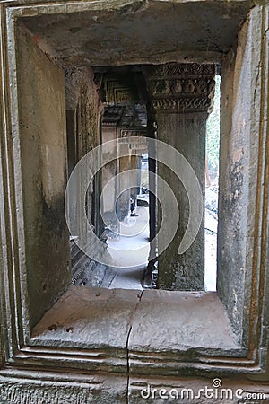 Looking through a window at stone pillar in famous histroical angkor wat ruins, cambodia Stock Photo