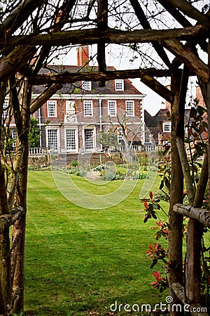 Looking through a garden archway at a mansion house Stock Photo