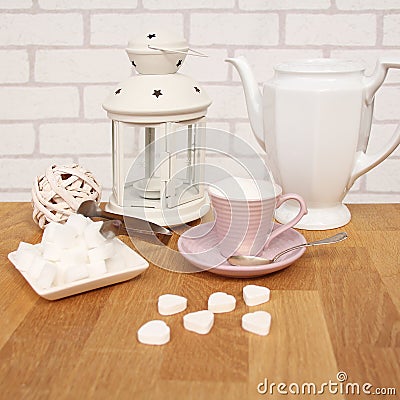 Loose sugar in a tea cup with saucer, refined slices, sugar tongs, white coffee pot and interior lamp, concept of excess sugar Stock Photo