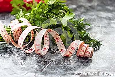 Loose weight, dieting concept. Parsley, dill, red pepper and measuring tape on black, white background Stock Photo