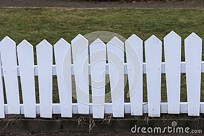 Lopsided white painted wood fence, grass in the back Stock Photo