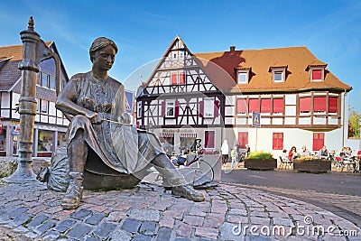 Lorsch, Germany, Fountain called `Tabakbrunnen` showing a tobacco seamstress at town square with traditional half timbered buildin Editorial Stock Photo