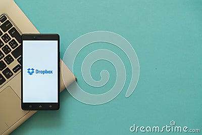 Dropbox logo on smartphone placed on laptop keyboard. Editorial Stock Photo