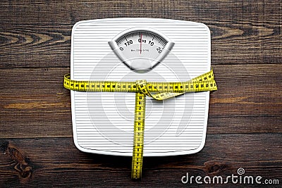 Lose weight concept. Scale and measuring tape on dark wooden background top view Stock Photo