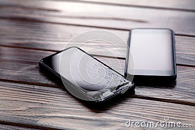 Ð¡loseup black smartphone with broken screen glass lying on wooden table. Concept of dropping phone, broken gadget, electronics Stock Photo