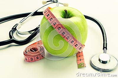 Losing weight - green apple, measuring tape and stethoscope Stock Photo