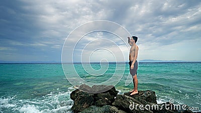 Lost alone male teen standing on sea rock Stock Photo