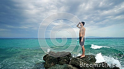 Lost alone male teen standing on sea rock Stock Photo