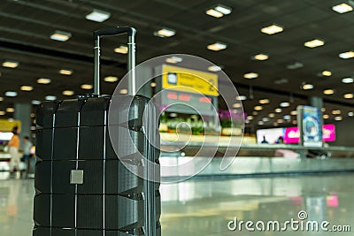 Lost black hardshell carry-on roller luggage left unattended at the baggage reclaim area at airport Stock Photo