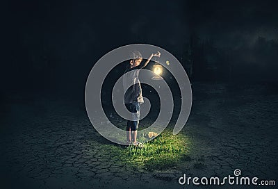 Lost child holding an old lamp in an apocalyptic environment Stock Photo