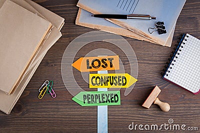 Lost, confused and perplexed concept. Paper signpost on a wooden desk Stock Photo