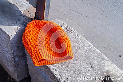 A lost orange women`s knitted hat lies on a concrete block Stock Photo