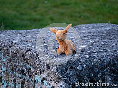 Lost stuffed animal that looks like a bamby toy sitting on a stone Stock Photo