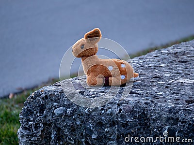 Lost stuffed animal that looks like a bamby toy sitting on a stone Stock Photo