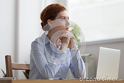 Lost in thoughts woman sits at workplace desk in office Stock Photo